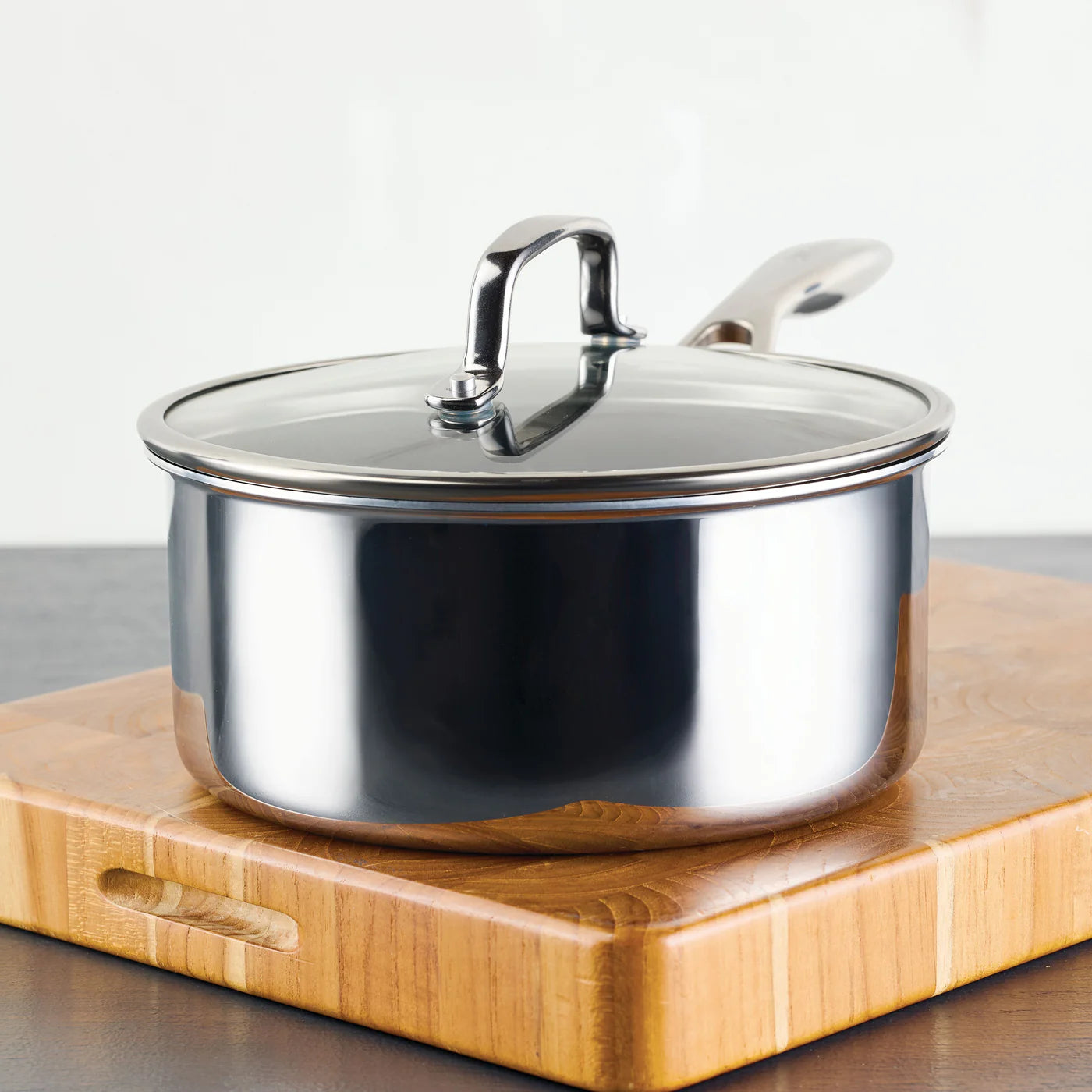 Stainless steel pot with lid on a wooden cutting board